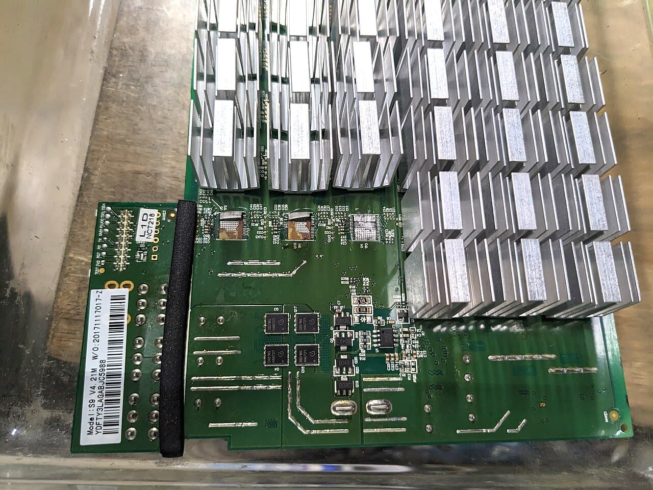 A green circuit board with rows of small aluminium heatsinks over its chips